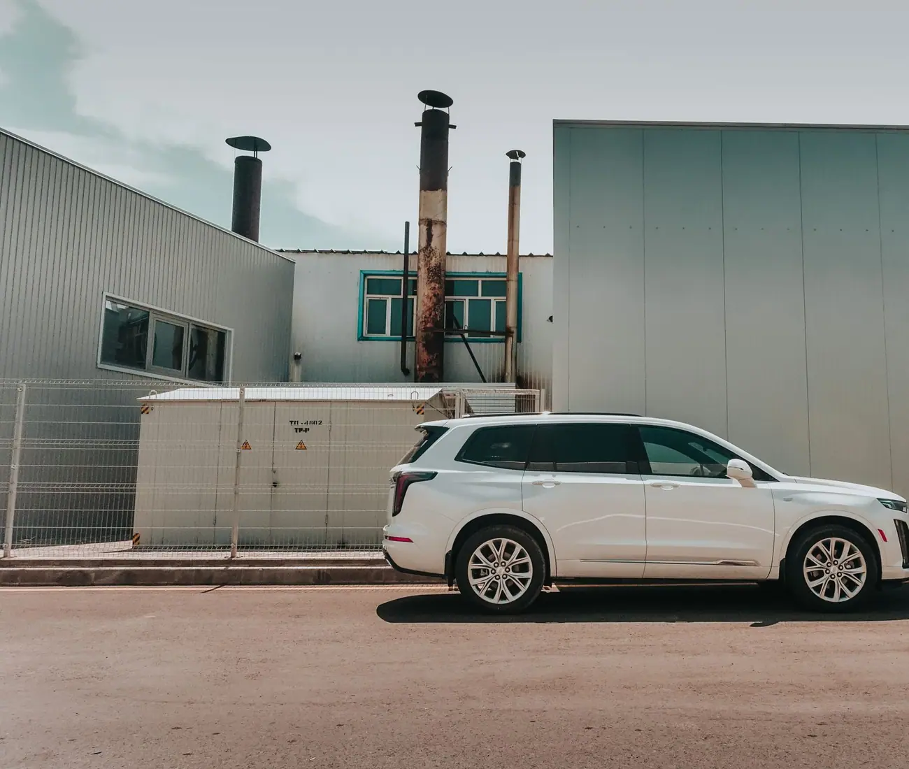 A white SUV parked side on against an industrial building
