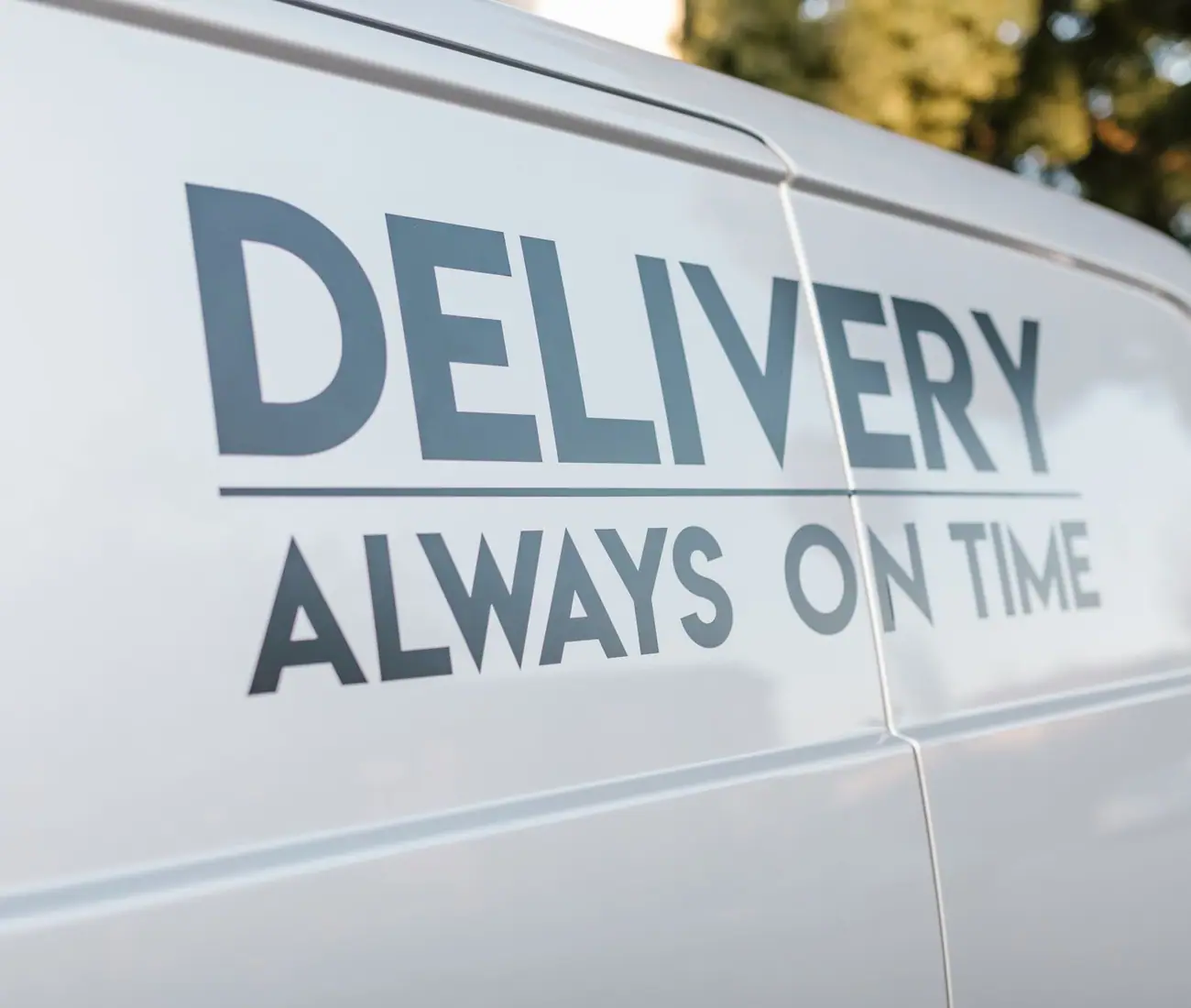 The flank of a white van carrying cut vinyl lettering that reads DELIVERY, ALWAYS ON TIME