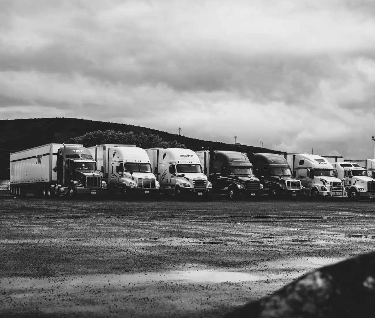 A row of parked tractor units in a yard, in black and white