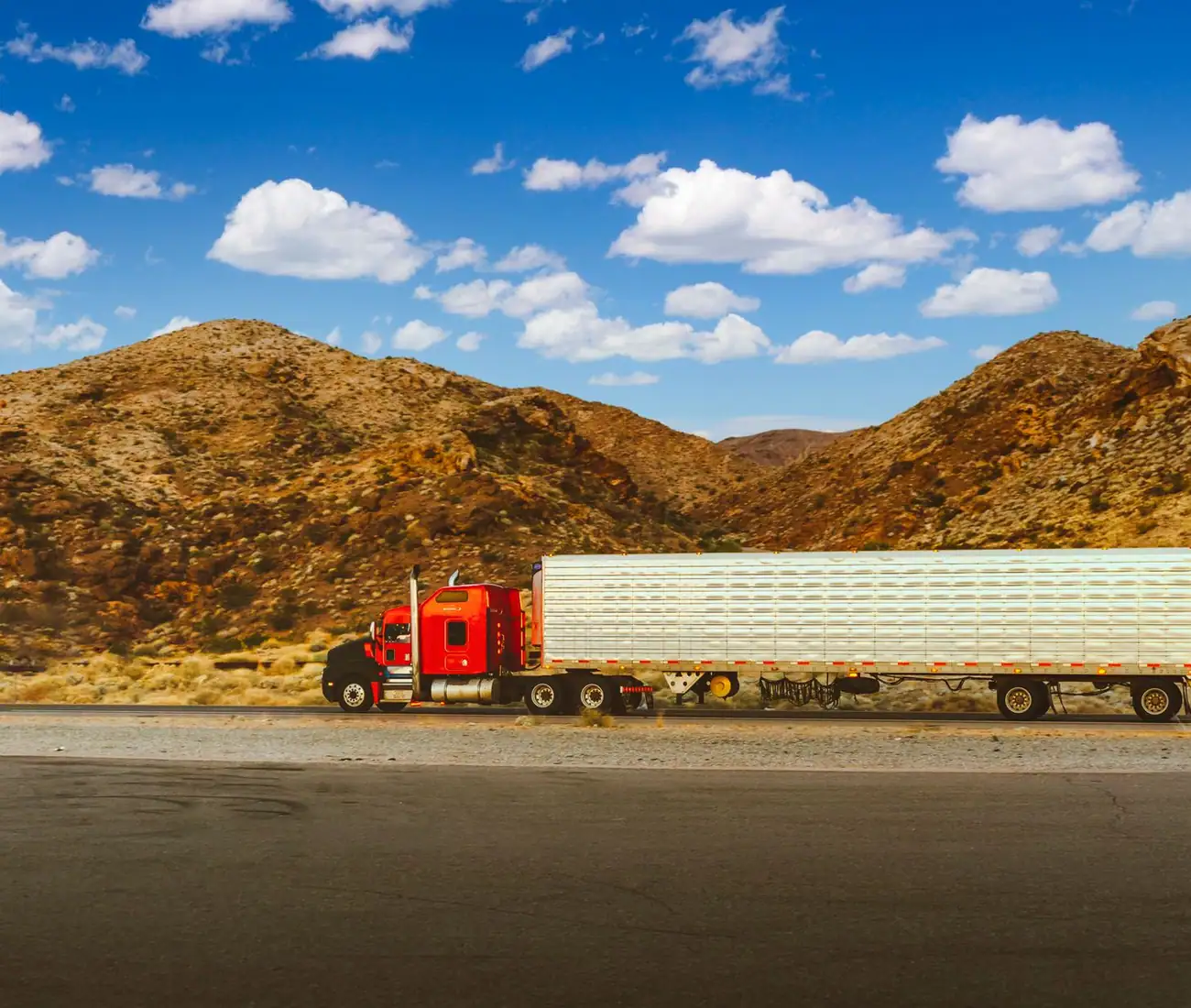A tractor unit and trailer running a desert highway, seen side on