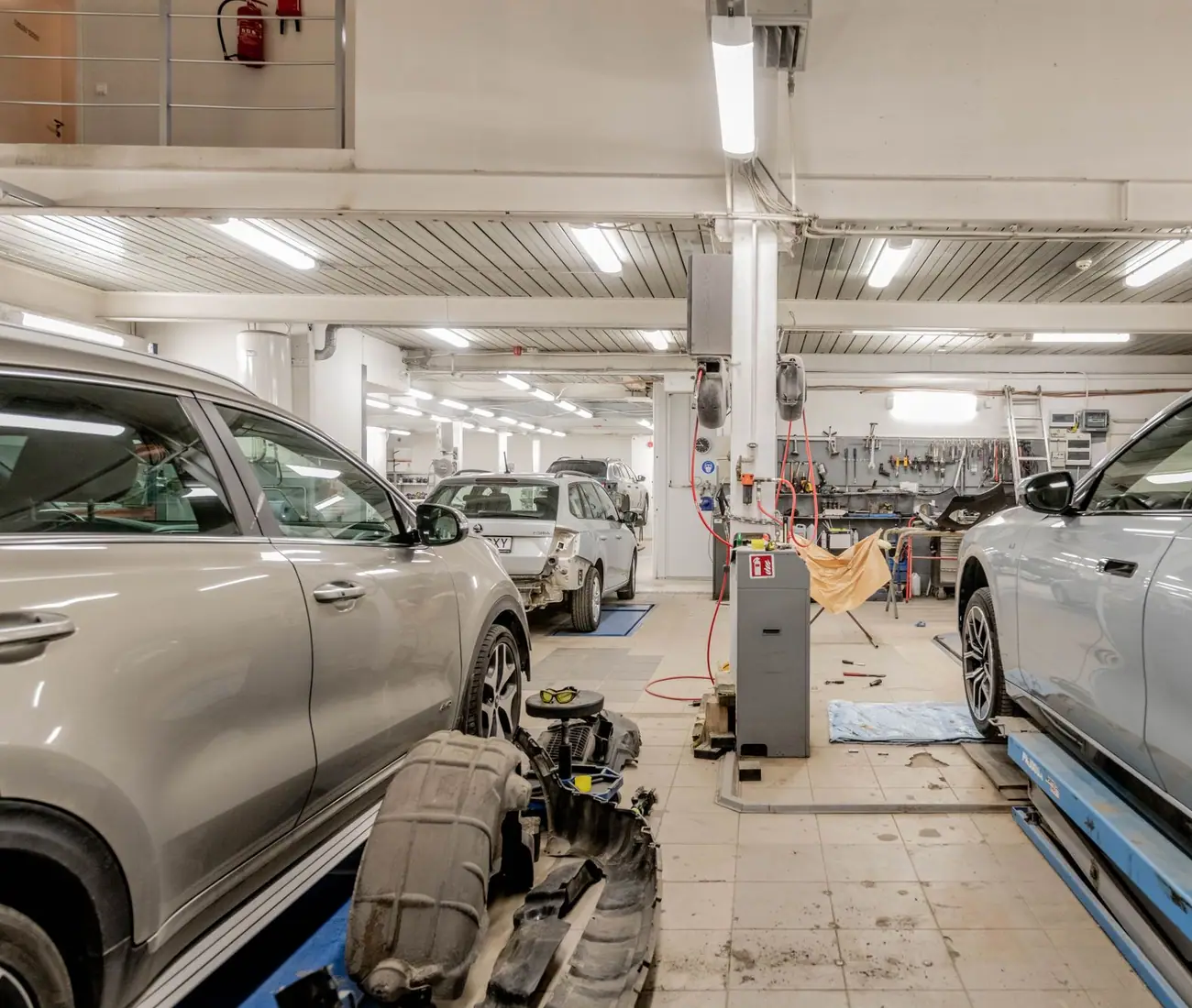 A line of vehicles inside a service building under strip lighting