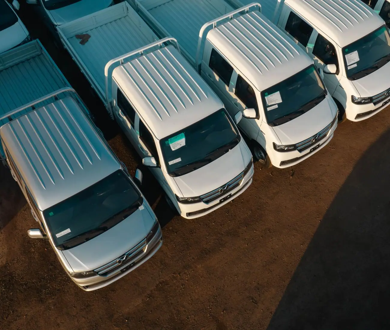 An aerial row of unmarked white pickups parked in a lot
