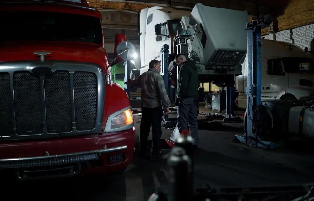 A commercial truck in a workshop bay, crew working around it