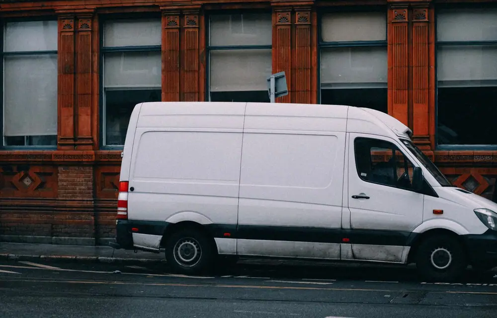 A plain white cargo van parked kerbside, its long side panel unmarked
